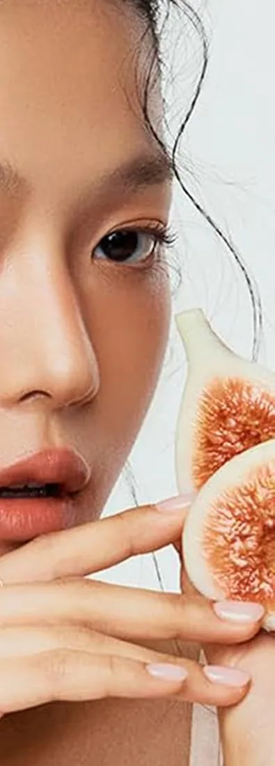 A model wearing TFIT Fluffy Velvet Cushion Blush in N02 Fig Nude, holding a fig